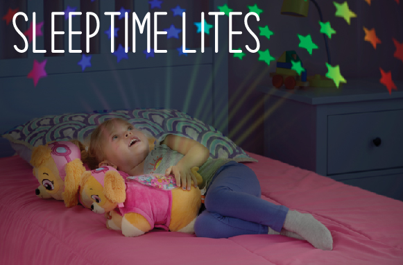Click here to shop Sleeptime Lites, showing a little girl gazing up at the rainbow stars on her ceiling from the Nickelodeon Paw Patrol pink puppy Skye Sleeptime Lite.